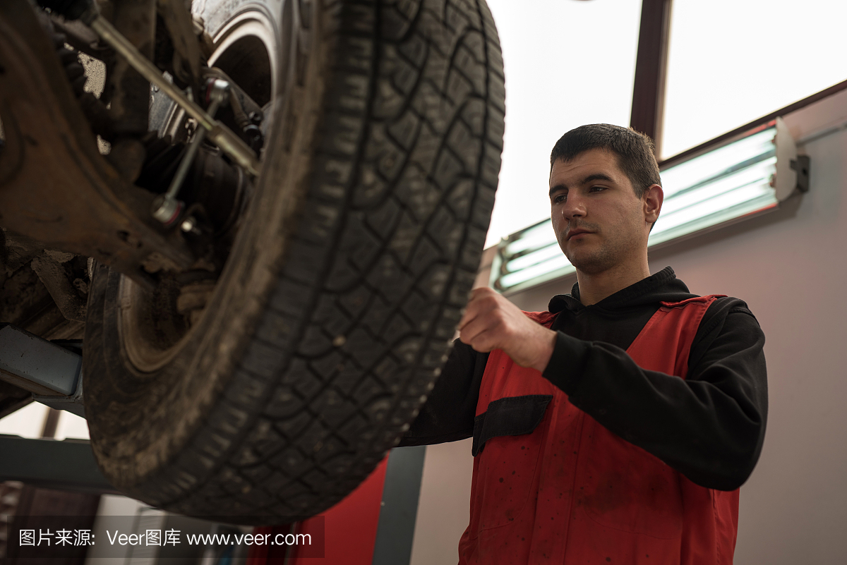 年轻的机修工正在汽车修理厂修理一个轮胎。